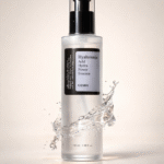 COSRX Hyaluronic Acid Hydra Power Essence 100ml in clear pump bottle with water splash background